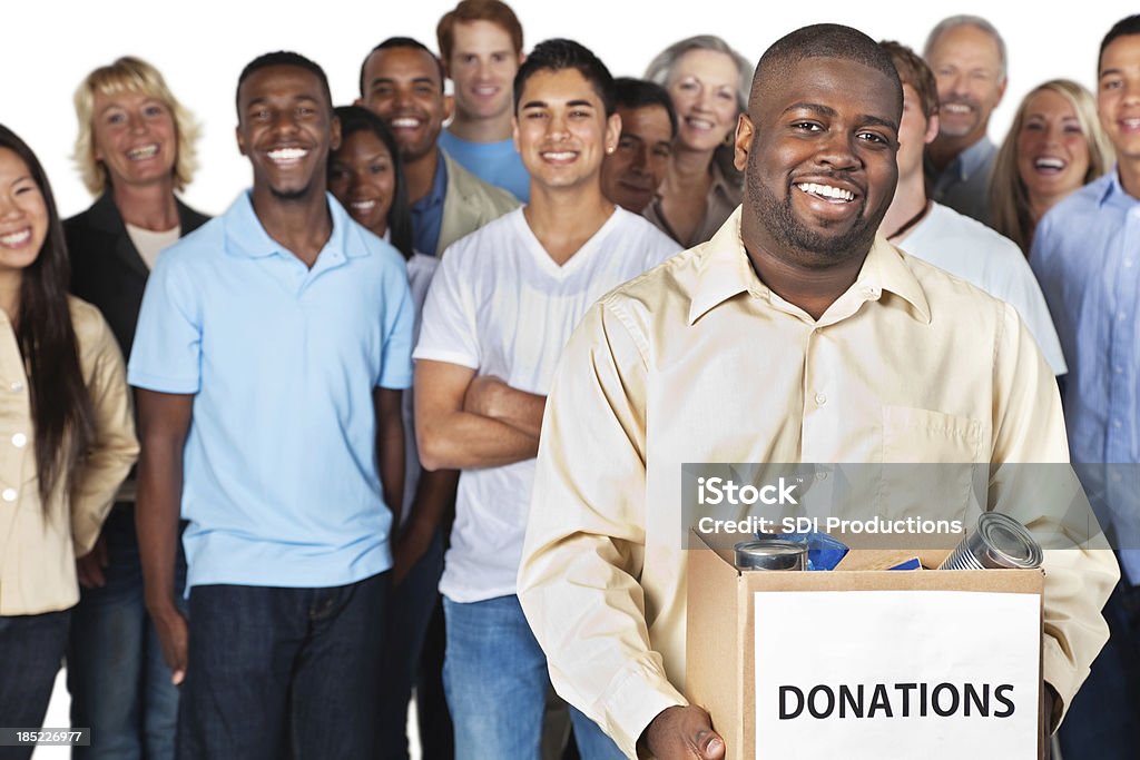 Hombre que agarra caja de donaciones con grupo detrás de él - Foto de stock de Meals On Wheels libre de derechos