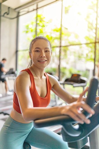 Asian Woman Doing Cycling Exercise on Stationary Bike at a Local Indoor Fitness Gym Club