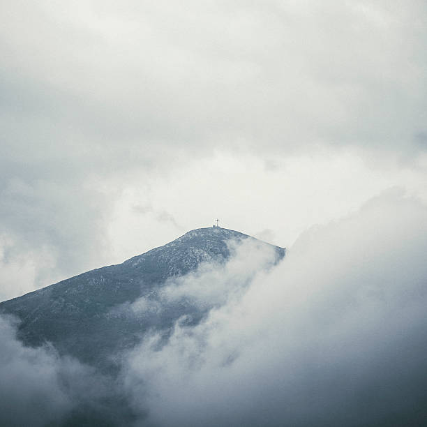 Cross on the top of the hill surrounded by clouds.