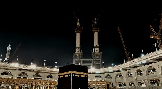 A landscape view of Kaaba and the building of Al-Masjid Al-Haram at night.