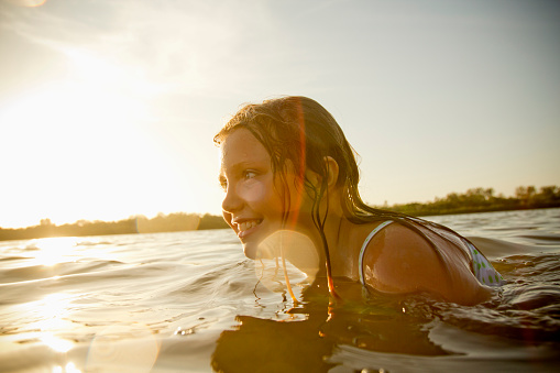 Image of a girl playing in the water of a bay / lake / sea at sunset. Photo was taken backlit with nice natural lens flare (ISO 160). All my images have been processed in 16 Bits and transfer down to 8 before uploading.  