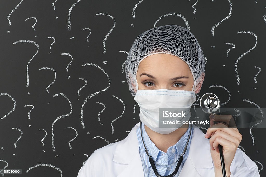 Female doctor with stethoscope in front of question marks Female doctor with stethoscope in front of question marks on blackboard Adult Stock Photo