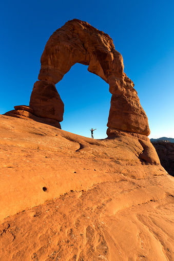 traveller waiting for sunset at Delicate Arch in Arches National Park, Moab, Utah, USA