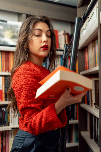 istock Young woman choosing books in the library 1852310636