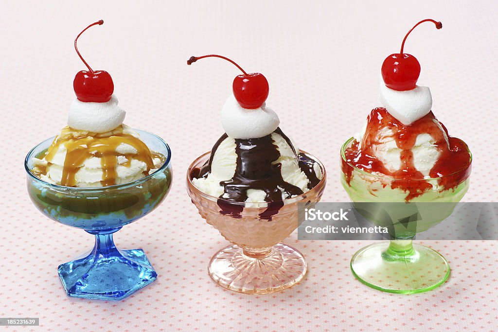 Three Ice Cream Sundaes in Vintage Glass Dishes "Three ice cream sundaes with caramel, hot fudge and berry sauce; topped with whipped cream and cherries in vintage glass dishes." Ice Cream Sundae Stock Photo