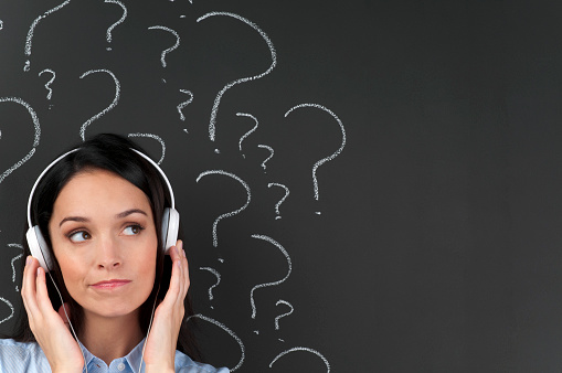 Attractive woman listening to music with question marks on a blackboard with copy space