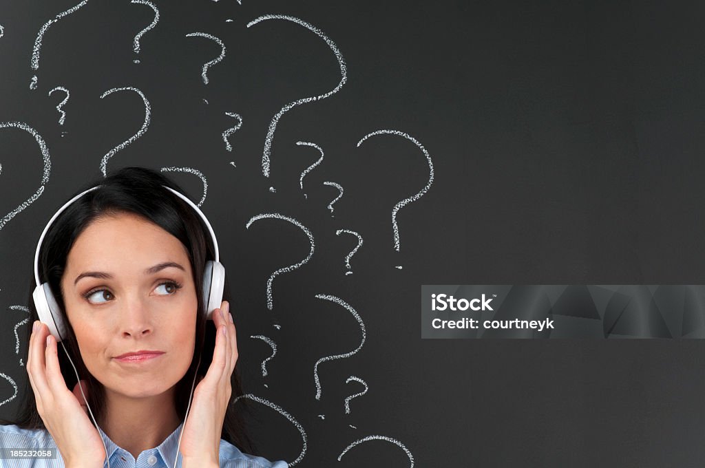 Music choice concept. Listening with question marks Attractive woman listening to music with question marks on a blackboard with copy space Asking Stock Photo
