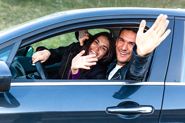 istock Young couple waving from car 185232647
