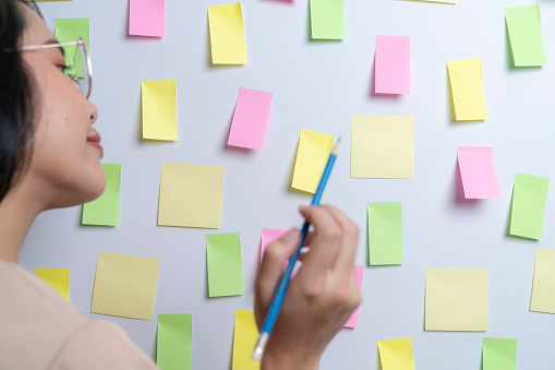 A young woman write a to-do list on sticky note