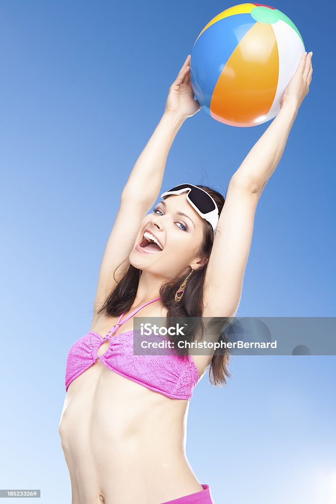 Donna sorridente con Palla da spiaggia in aria - Foto stock royalty-free di 20-24 anni