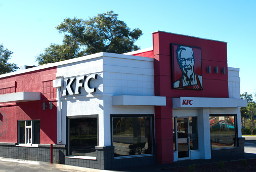 Ocala, Florida USA - October 22, 2023 22, 2023 KFC Kentucky fried chicken is a chain of fast food casual dining restaurant selling chicken wings, fingers, sandwiches and salads on blue sky background