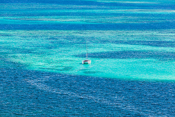 Lonely Catamaran, The Grenadines Lonely catamaran in the turquoise waters of the Caribbean sea around the Tobago Cays. St. Vincent and the Grenadines. Canon EOS 5D Mark II tobago cays stock pictures, royalty-free photos & images