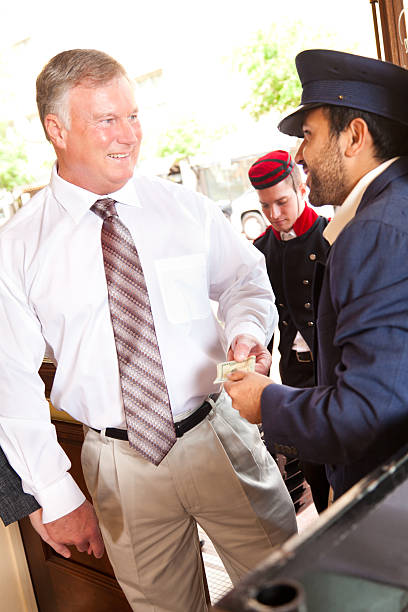 Mature man giving hotel door-man a tip Mature man giving hotel door man a tip. door attendant photos stock pictures, royalty-free photos & images
