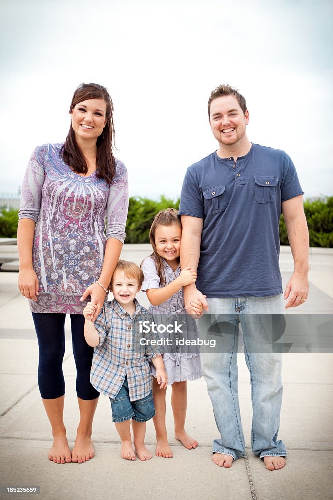 Família Jovem feliz, segurando as mãos enquanto ficam em pé do lado de fora - Foto de stock de 2-3 Anos royalty-free