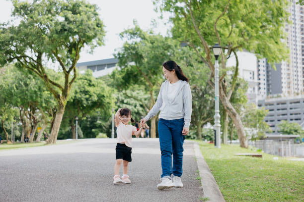 istock Mother and young daughter walking in public park 1852361400