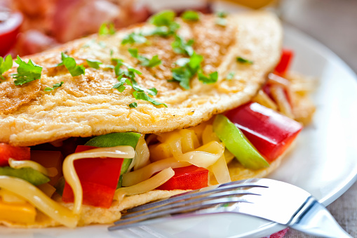 Omlet with vegetables, cheese and bacon, close-up
