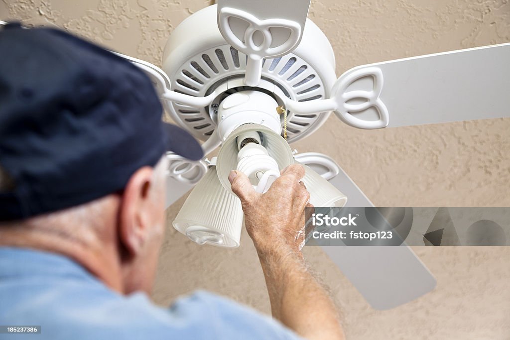 Electrician changing out light bulbs to eco-friendly compact fluorescent Electrician changing out light bulbs to eco-friendly compact fluorescent bulbs Ceiling Fan Stock Photo