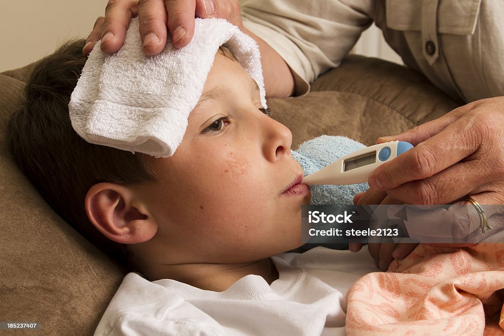 Sick Child "A sick, young boy having his temperature taken by his grandma." Adult Stock Photo