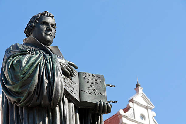 Church Reformer Martin Luther "Monument of Martin Luther in Wittenberg, Germany. It was the first public monument of the great reformer, designed 1821 by Johann Gottfried Schadow. Martin Luther (1483-1546) was a German monk, theologian, and church reformer and the translator of the bible into German. He is also considered to be the founder of Protestantism. He lived and worked many years in Wittenberg." monk religious occupation photos stock pictures, royalty-free photos & images