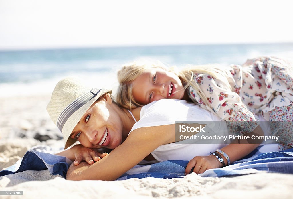 Bonding time together Daughter lying on mom's back on beach Adult Stock Photo