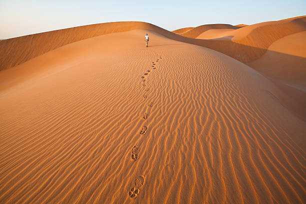 Walking in the sand dunes with foot prints "Walking in the sand dunes of Rub al Khali desert Oman," oman stock pictures, royalty-free photos & images