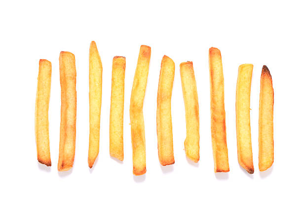 Macro closeup of frozen uncooked raw straight cut salty french fries pommes frites on oven baking tray before cooking or frying with texture detail