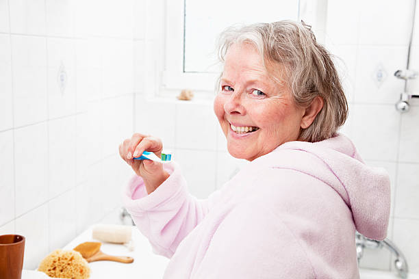 istock senior woman brushing teeth 185238816