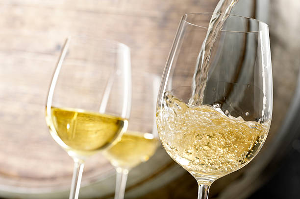 White Wine Pour Close up of white wine being poured in a cellar with an oak barrel in background. white wine photos stock pictures, royalty-free photos & images