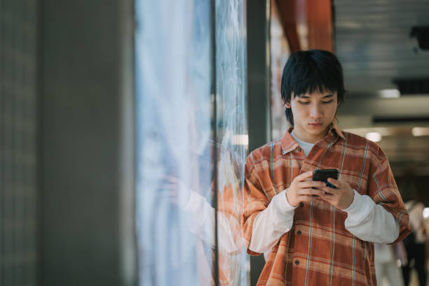 asiatischer chinesischer junger mann, der sich in der u-bahn-station an ein schild lehnt - hong kong billboard asia china stock-fotos und bilder