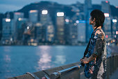 Asian Chinese young man tourist with mirrorless camera standing in front of kowloon bay