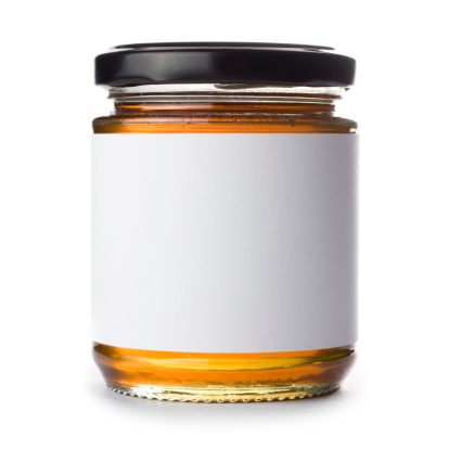 Jar of honey with a blank label isolated on a white background. Ideal for imposing your own artwork onto.