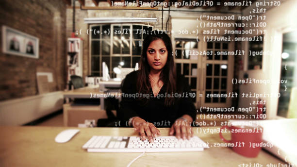 Computer programmer typing code Wide angle portrait of a computer programmer sitting at her desk typing code which appears on the monitor in front of her.  Camera takes the point of view of the monitor. extensible markup language photos stock pictures, royalty-free photos & images