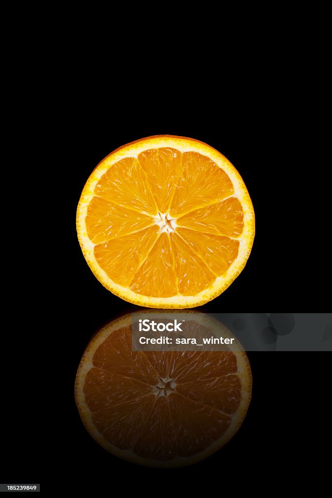 Demi-orange sur un fond noir réfléchissant - Photo de Agrume libre de droits