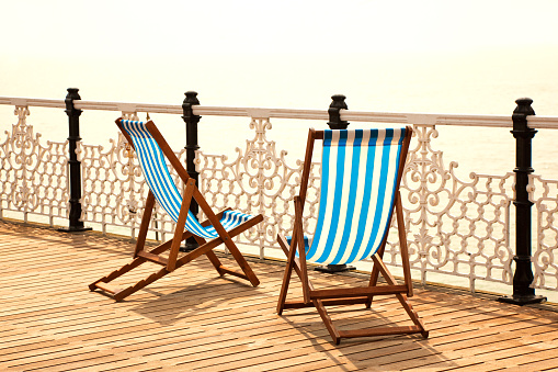 Two people sitting in deck chairs in a park. Rear view; shadows only. Sunny weather. Photo was made in London, England.