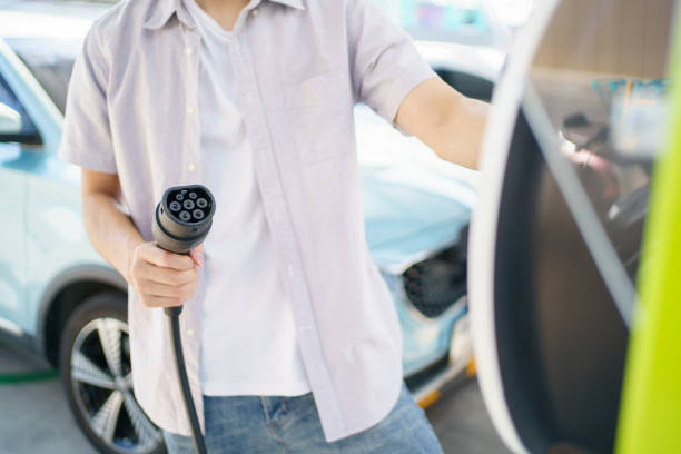 istock Man charging EV car at public charging station. 1852400128