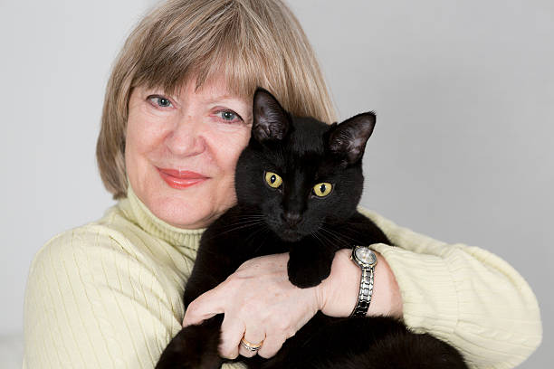 istock Senior woman holding black cat 185240335