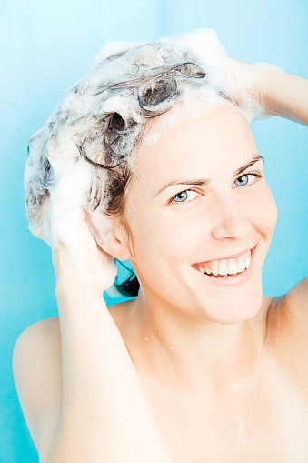 Beautiful young woman enjoying the shower, washing her hair.
