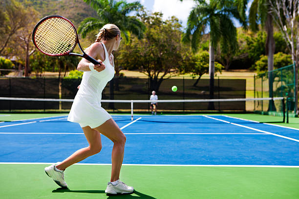 people playing tennis in tropics stock photo