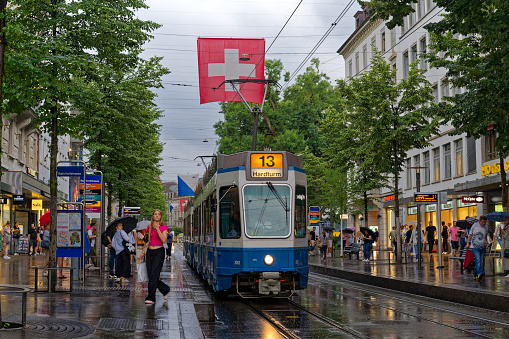 Famous shopping mille Bahnhofstrasse at City of Zürich during rush hour with shops, tram and pedestrians on a rainy summer day. Photo taken July 12th, 2023, Zurich, Switzerland.