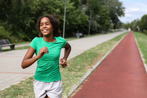 Girl running on a track field. About 12 years old, African female.