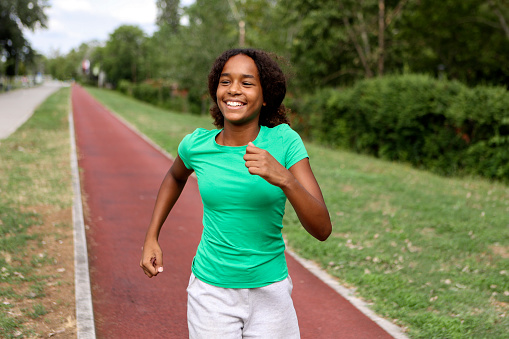Girl running on a track field. About 12 years old, African female.