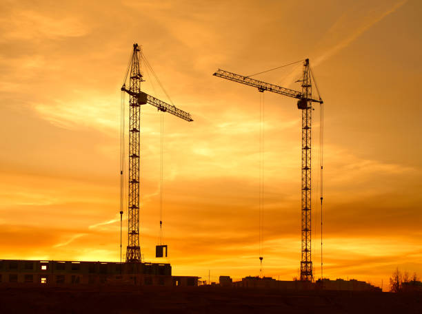 istock Tower cranes silhouette at construction site against yellow sunset 1852426510