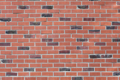 Masonry wall of various shades of red bricks.