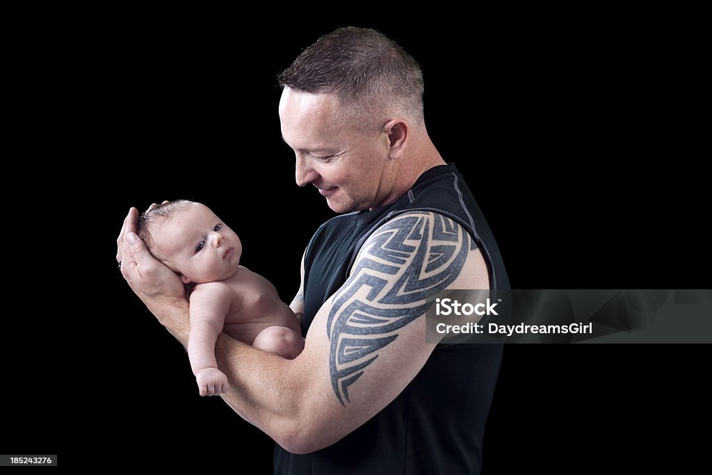 Father Holding Baby on Black Background Father with tattoo design on arm holding newborn baby on black background. Baby - Human Age Stock Photo