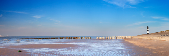A lighthouse on a beach. A seamlessly stitched panoramic image.