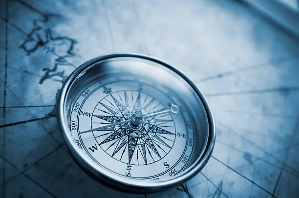 Compass on old map with blue tone.