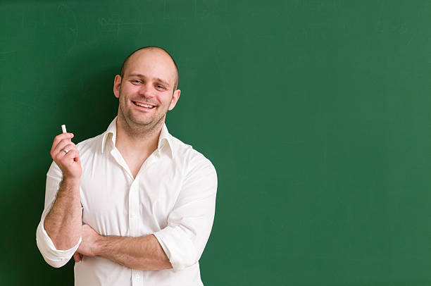 istock smiling teacher leaning at blackboard 185243758
