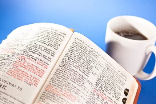 Open Bible on table with coffee mug    