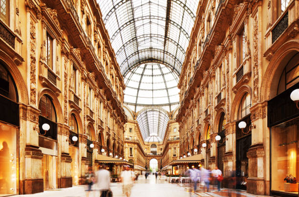 Galleria Vittorio Emanuele II in Milano, Italy Shot of the famous Galleria Vittorio Emanuele II in Milano, Italy, showing the spectacular view of an almost golden gate to luxury. Long exposure for motion blurred people rushing through. galleria vittorio emanuele ii stock pictures, royalty-free photos & images