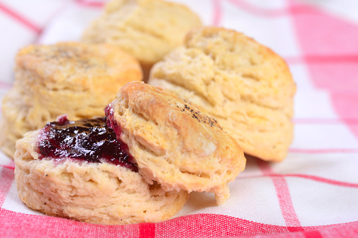 A homemade southern biscuit with blueberry preserves with extra biscuits in the background.